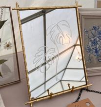 Load image into Gallery viewer, A side angel of Handmade mirror with a stunning hand-engraved Monstera leaf design, crafted from golden metal, combining functionality with artistic flair to brighten up any home.