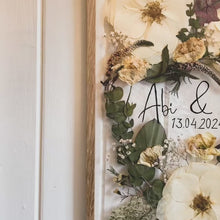 Load and play video in Gallery viewer, An overview of Handcrafted pressed flower frame for wedding preservation. Handwritten couples name and date featured. With a wedding bouquet secured in place, perfect for home decor.