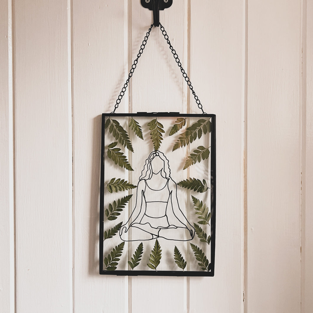 Handcrafted pressed flower frame featuring a drawing of a woman meditating, dried fern leaves inside the Black frame, perfect for home decor.