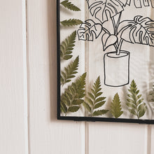 Load image into Gallery viewer, A corner angle of Handcrafted pressed flower frame featuring hand drawn Monstera Leaf. With fern leaves circling the drawing in a black glass frame, perfect for home decor
