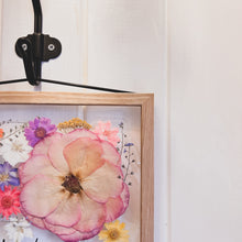 Load image into Gallery viewer, A close up of the corner of handcrafted pressed flower frame featuring vibrant pink hues, perfect for home decor.
