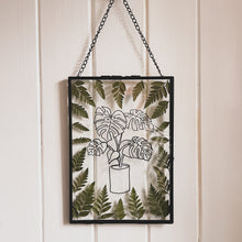 Load image into Gallery viewer, Handcrafted pressed flower frame featuring hand drawn Monstera Leaf. With fern leaves circling the drawing in a black glass frame, perfect for home decor
