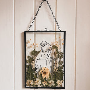 Handcrafted pressed flower frame featuring hand drawn back of a woman. With fern leaves and flowers in a black glass frame, perfect for home decor